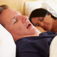 A man and a woman are sleeping in bed, with the man snoring—raising the classic concern of sleep sound issues, one of the disorders of interest. A man and a woman are sleeping in bed, with the man snoring—raising the classic concern of sleep sound issues, one of the disorders of interest.