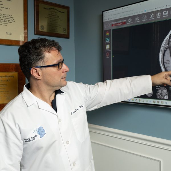 In his office adorned with framed certificates, a doctor from Three Village Neurology, wearing a white coat, points to a brain scan on the screen, exemplifying the clinic's commitment to exceptional neurological care. In his office adorned with framed certificates, a doctor from Three Village Neurology, wearing a white coat, points to a brain scan on the screen, exemplifying the clinic's commitment to exceptional neurological care.