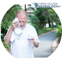 An elderly man walks along the path, wiping sweat with a towel and holding a water bottle, battling the intensity of the summer heat.