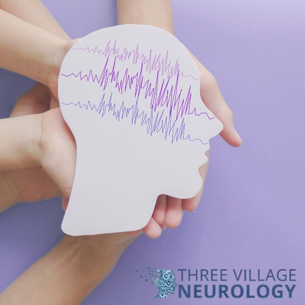Hands hold a cutout of a human head with brainwave patterns drawn on it, illustrating facts about epilepsy; Three Village Neurology logo is visible in the bottom right corner.